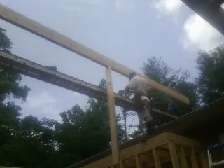 Carpenter setting a ridge beam over a new addition frame — Ice Dam Removal by Roofing Brothers in Travis Afb
