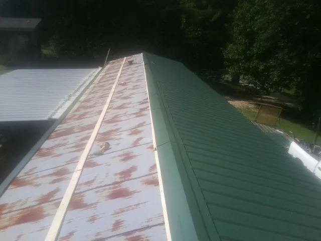 Old rusted panels beside newly installed green metal roofing — Wind Damage Roof Repair by Roofing Brothers in Travis Afb