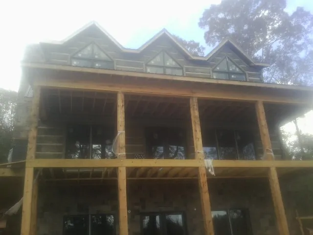 Dormers and porch framing on a large log home under construction — Roof Coating work by our crew in Travis Afb
