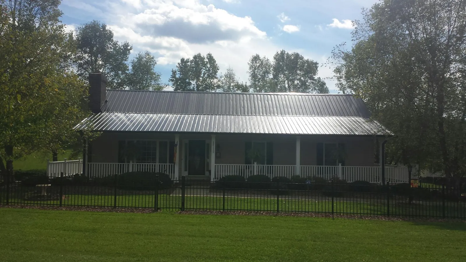 Gray metal roof on a brick ranch with a full width front porch — Gutter Guard Installation work by our crew in Travis Afb