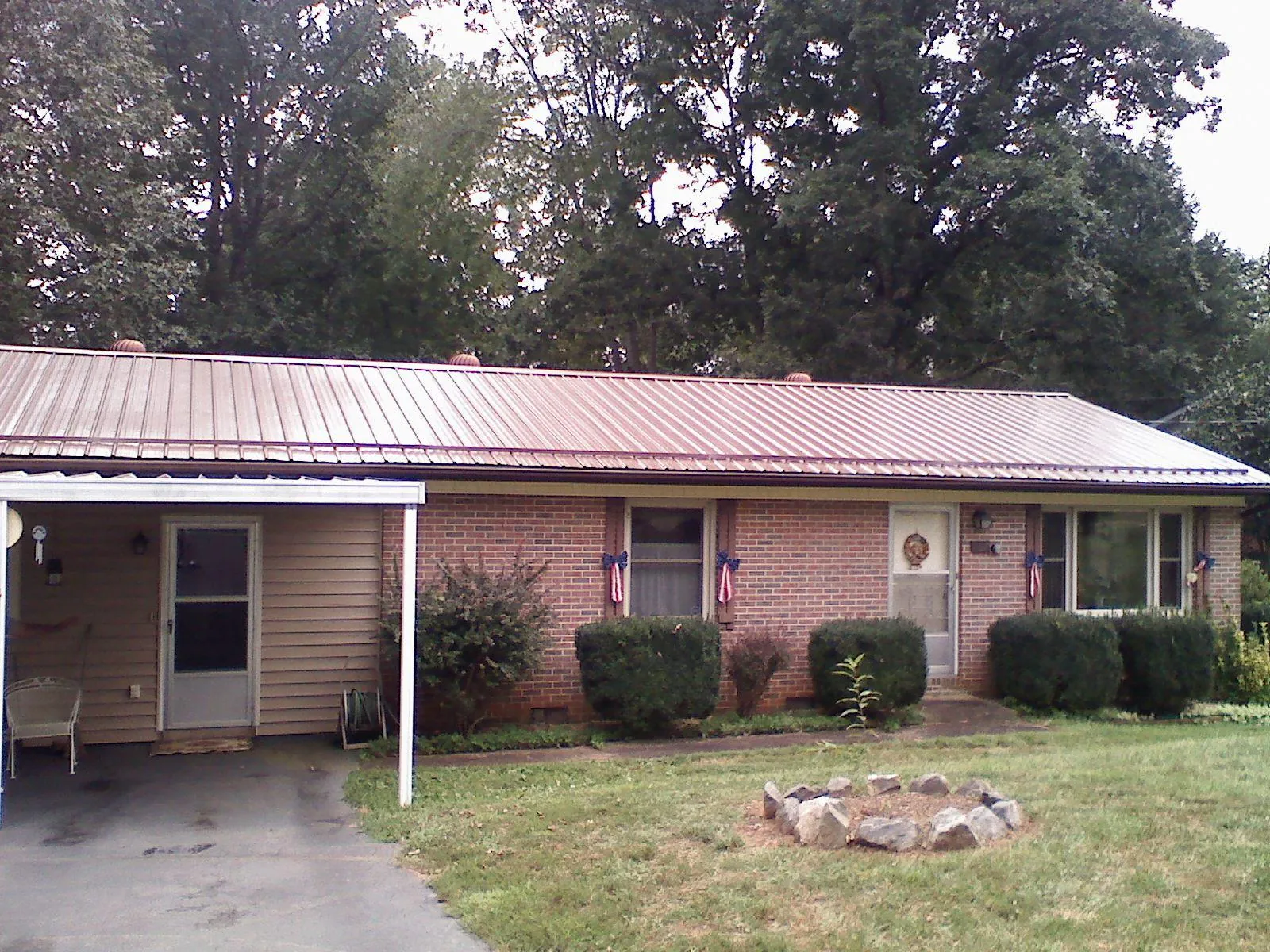 Bronze metal roof and carport on a brick ranch home — Roof Repair work by our crew in Travis Afb