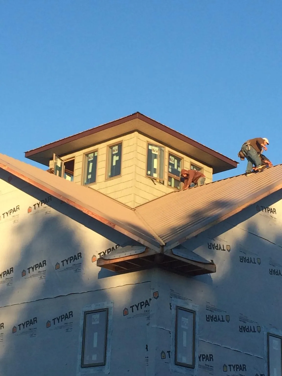 Roofers working around a rooftop cupola on a new metal roof at sunset — Roof Waterproofing in Travis Afb by Roofing Brothers